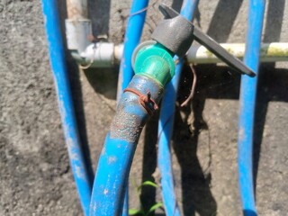 A close-up shot of a metal water faucet with a garden hose attached, ready for use.