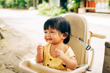 Joyful baby girl high chair family life moments outdoor setting asian culture children's happiness