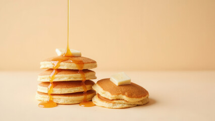 Freshly made pancakes with butter and maple syrup pouring down with pastel background and copy space