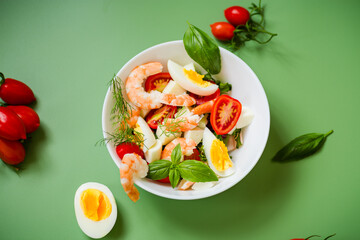 Culinary composition with shrimps, eggs and cheese on a green background