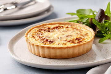Golden Quiche Lorraine with bacon and cheese on elegant modern table, bright style