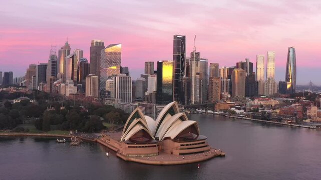 Bright pink sunrise colours over Sydney city urban high-rise towers on harbour waterfront.