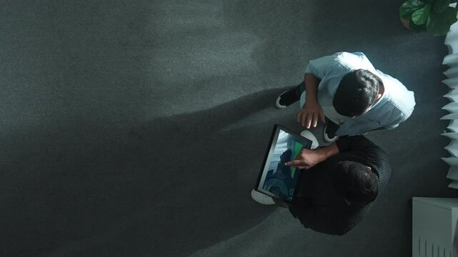 Top down view of manager stand with investor while holding tablet and looking at financial statistic. Leader talking and giving advise about increase stock market chart display on tablet. Convocation.