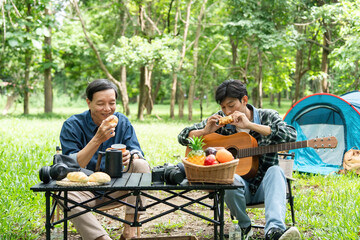Family meal outdoors. Father and son enjoying food and music during a camping trip.