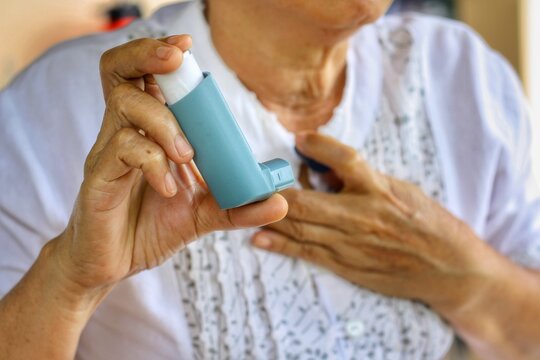 Elderly Female's hand holding inhaler with blurred background.Medication for relief bronchospasm or Dyspnea from asthma attack or allergy,that's an emergency condition.Healthcare and medical concept.