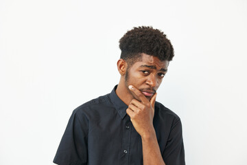 Thoughtful African American man posing confidently with a hand on his chin, wearing a casual black...