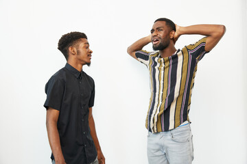 Two black men expressing a range of emotions, one laughing joyfully while the other listens in a...