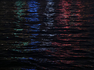 The colorful city lights create beautiful reflections in the water at night
