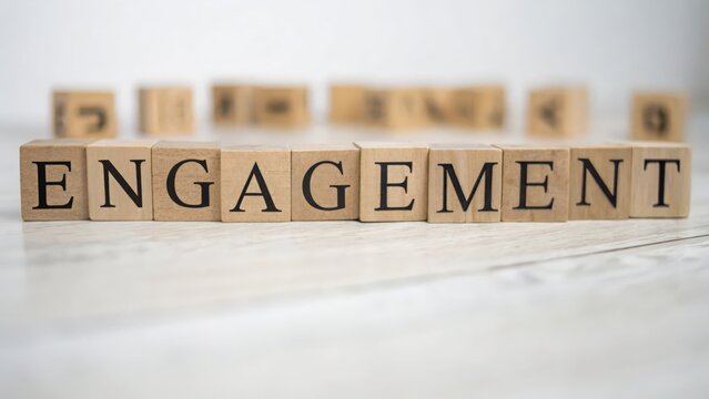Wooden cubes spelling "ENGAGEMENT" with defocused social media metrics behind