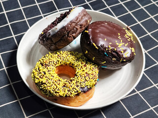 Three delicious donuts topped with sprinkles and various colored glazes, displaying a tempting...