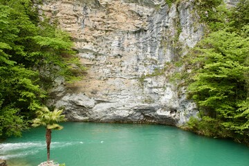 A magical turquoise, crystal clear lake, high in the mountains near a steep cliff.