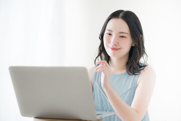 Cute camera-ready woman in front of computer Thinking Positive Image of Sleeveless White Back in Spring/Summer