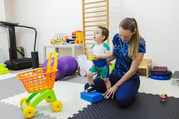Young boy receives supportive assistance during a physical rehabilitation session aimed at...