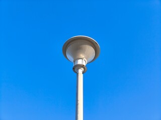 A round lamp with a white pole stands against a blue sky background