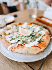 Delicious freshly baked pizza with toppings and a slice of lemon on a table