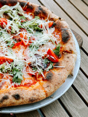 Freshly baked pizza topped with vegetables served on a wooden table