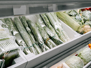 Fresh organic herbs and vegetables displayed in a grocery store cooler section
