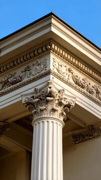 Classical architecture detail showcasing column capital with acanthus leaves and decorative frieze against blue sky