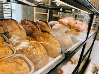 Freshly baked artisan bread displayed in a local bakery case during daytime hours