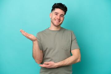 Young caucasian man isolated on blue background extending hands to the side for inviting to come