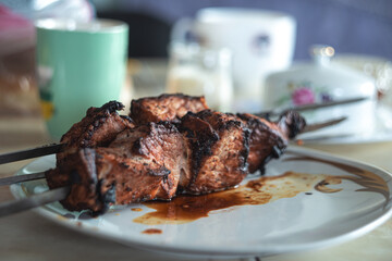 Burnt meat on skewers lies on a plate. Spoiled meat dish. High quality photo