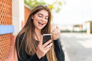 Young pretty caucasian woman with phone in victory position