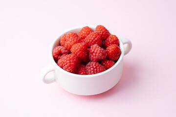 Bowl of fresh raspberries on pink for snack or breakfast concept
