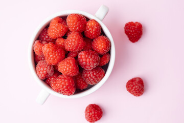 Top view of raspberries in a bowl  on pink background for diet blog or fruit branding concept