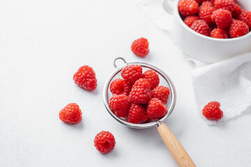 Raspberries in and around strainer on marble for recipe prep or organic diet concept