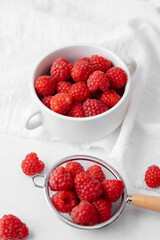 Raspberries in bowl and strainer on satin cloth for luxury food or dessert concept