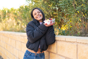 Young woman  holding a bowl of fruit at outdoors