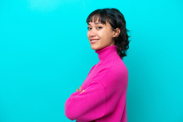 Young Argentinian woman isolated on blue background with arms crossed and looking forward