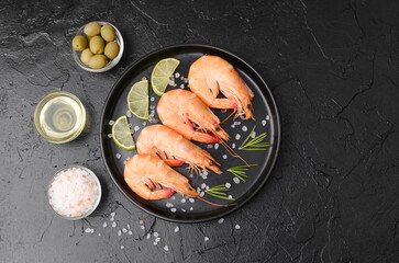Shrimp served with rosemary, salt and olives on black plate for gourmet appetizer or restaurant...