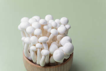 Shimeji mushrooms in wooden bowl on pastel background for organic harvest or rustic culinary concept