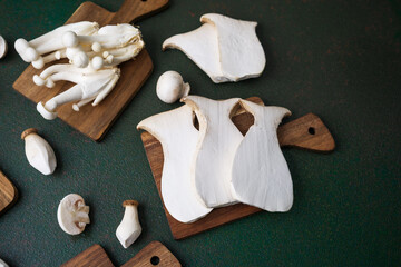 Assorted mushrooms on boards with dark green background for harvest variety or vegetarian cooking...