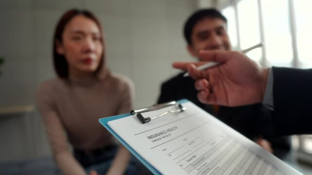 Close-up of a health questionnaire being filled out by a married couple
with an insurance agent. Financial planning for life insurance, health
coverage and retirement insurance.