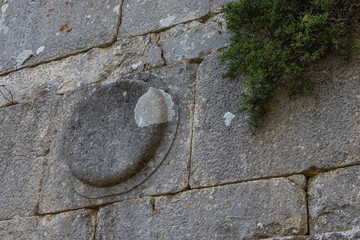 Termessos is an ancient city located in Turkey high in the mountains. The walls of the buildings in the ancient city are made of large smooth stone blocks. A round symbol is carved on the block.