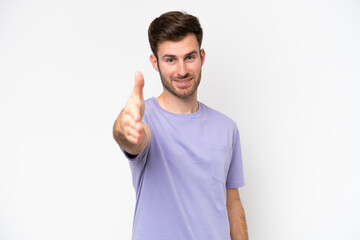 Young caucasian man isolated on white background shaking hands for closing a good deal