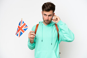 Young student caucasian man holding an United Kingdom flag isolated on white background frustrated...