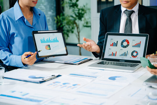 Businessman hand using smartphone, laptop and tablet with social network diagram and team colleagues discussing data on desk as concept i