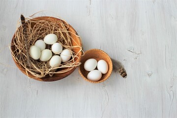 White eggs in a basket on a white wooden background. Top view.