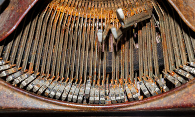 Close up of the typeface of an old rusty typewriter with some of the letters stuck in the up...