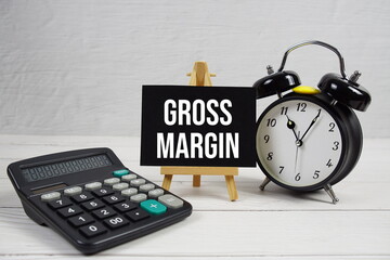 GM Gross Margin text with alarm clock on wooden background