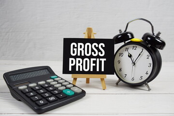 Gross Profit text with alarm clock on wooden background