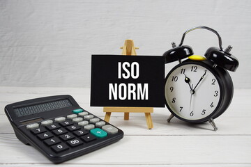 ISO NORM text with alarm clock on wooden background