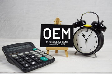 OEM Original Equipment Manufacturer text with alarm clock and calculator on wooden background