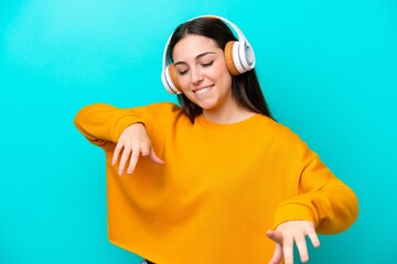 Young girl isolated on blue background listening music and dancing