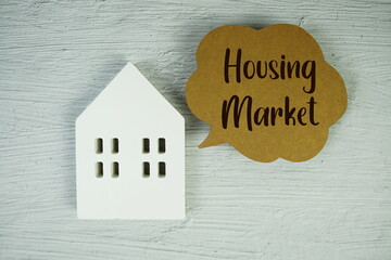 Housing Market text message with white house model on concrete background