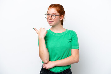 Young reddish woman isolated on white background pointing to the side to present a product