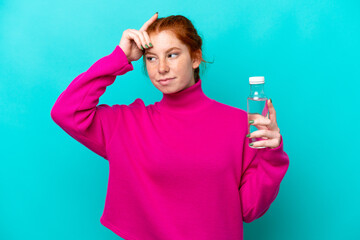 Young caucasian reddish woman with a bottle of water isolated on blue background having doubts and...